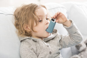 Small child using his inhaler device for asthma