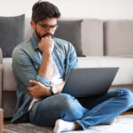 man sitting on the floor reading on his laptop
