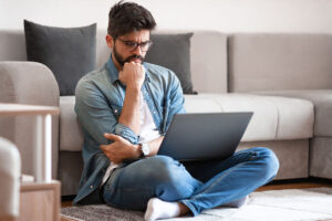 man sitting on the floor reading on his laptop