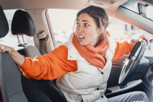 The annoyed female driver was backing up and accidentally hit a parked car. Accident and insurance