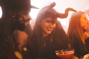 Couple in costume laughing over a cocktail at Chaminade’s 21+ Vampire Ball Halloween party in Santa Cruz