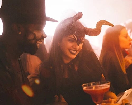 Couple in costume laughing over a cocktail at Chaminade’s 21+ Vampire Ball Halloween party in Santa Cruz