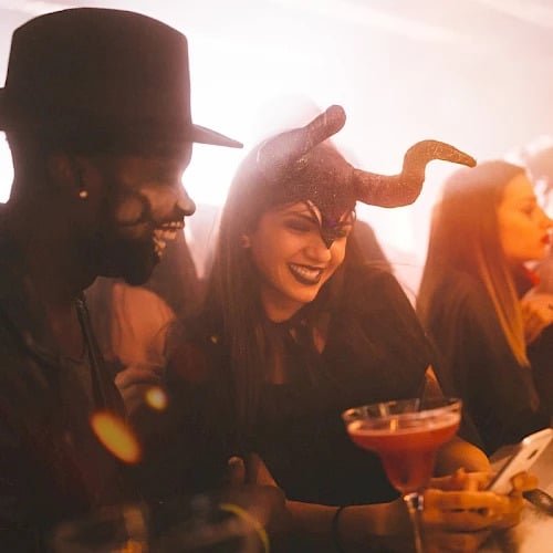 Couple in costume laughing over a cocktail at Chaminade’s 21+ Vampire Ball Halloween party in Santa Cruz
